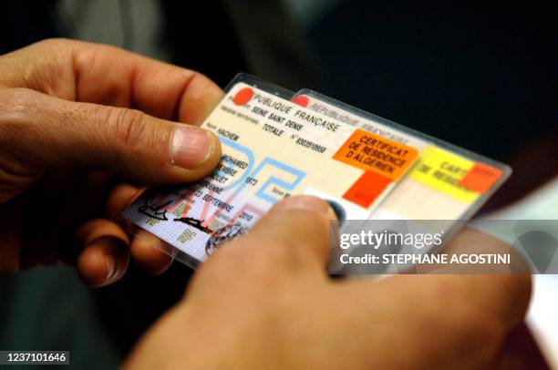 Un officier de la Police aux Frontières d'Ajaccio montre à la presse, le 03 février 2006 deux fausses cartes de séjour françaises, saisies, ainsi que...