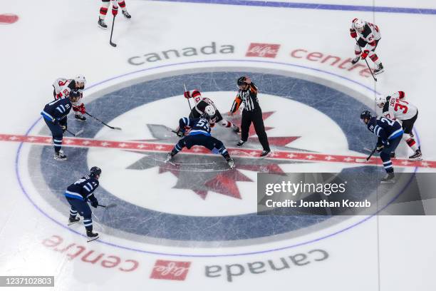 Mark Scheifele of the Winnipeg Jets and Nico Hischier of the New Jersey Devils take the opening face-off of the third period at Canada Life Centre on...