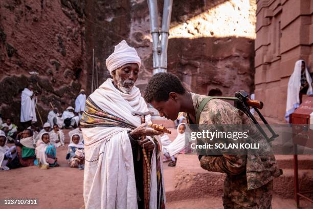 Soldier of the Amhara special forces kisses on a cross holded by an Ethiopian orthodox priest at a rock-hewn church in Lalibela, on December 7, 2021....