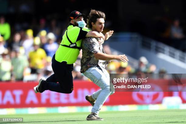 Security guard tackles a pitch invader during day two of the first Ashes cricket Test match between England and Australia at the Gabba in Brisbane on...