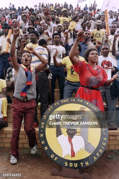 Union members sing songs and raise their fist during a rally by the National Union of Mineworkers at Jabulani stadium , on March 1, 1987 in Soweto.