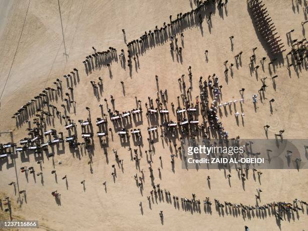 An aerial picture shows mourners carrying coffins during a mass funeral for Yazidi victims of the Islamic State group whose remains were found in a...