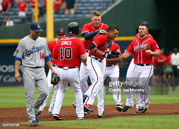 Martin Prado of the Atlanta Braves is mobbed by teammates Chipper Jones, Freddie Freeman and Dan Uggla of the Atlanta Braves after hitting a walk-off...