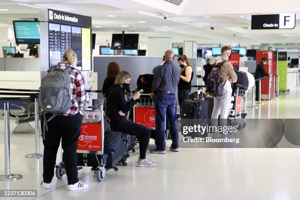 Passengers wait in line to check-in for flights inside the international departures terminal of Sydney Airport in Sydney, Australia, on Friday, Dec....