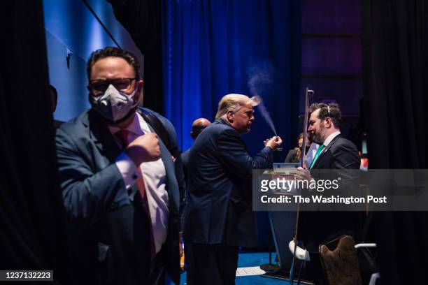 Former President Donald J Trump looks in a mirror and sprays his hair back stage moments before walking out to speak during the final day of the...