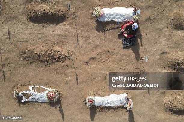 An aerial picture shows a mourner sitting next to one of the coffins during a mass funeral for Yazidi victims of the Islamic State group whose...