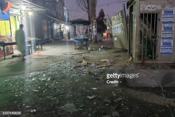 An Afghan man walks past shattered glass near the site of an explosion in Dasht-e-Barchi district in Kabul on December 10 after two people were...