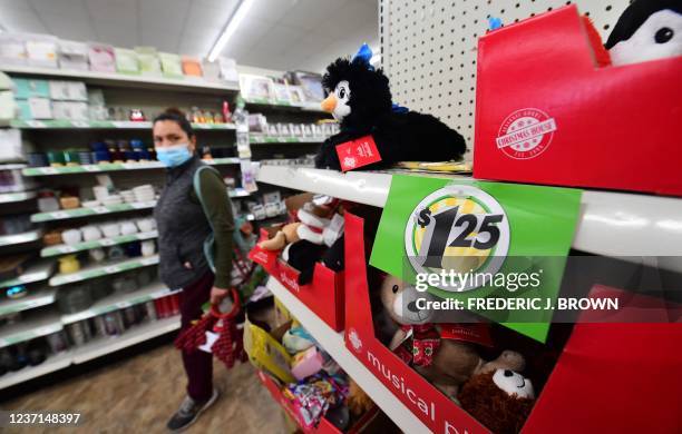 Shopper walks by a sign displaying $1.25 price, posted on the shelves of a Dollar Tree store in Alhambra, California, December 10, 2021. - The store...