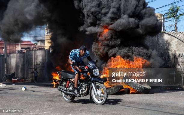 Motorcyclist drives past burning barricades erected by protesters in response to rising fuel prices, Port-au-Prince, Haiti, December 10, 2021.