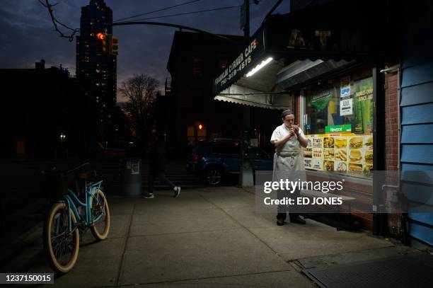 Deli worker lights a cigarette outside a bodega in Brooklyn, New York on December 10, 2021. - US consumer prices rose last month at a rate not seen...