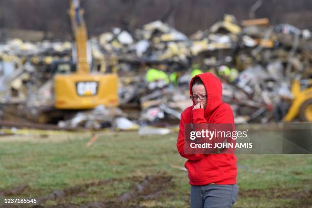 Woman walks away from what is left of the Mayfield Consumer Products Candle Factory as emergency workers comb the rubble after it was destroyed by a...