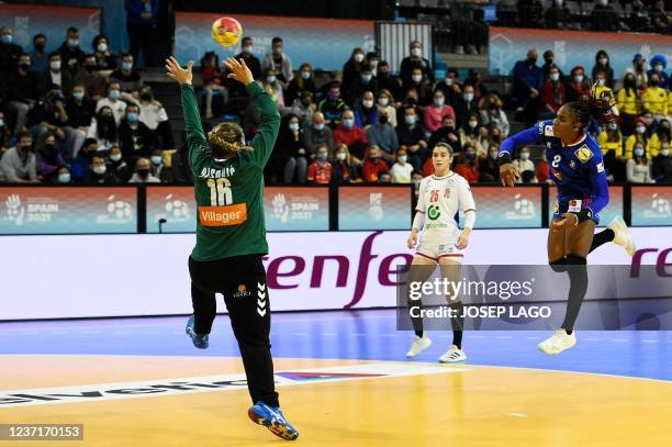 Serbia's goalkeeper Jovana Risovic jumps to stop the ball shot by 02 is challenged by France's left wing Coralie Lassource during the main round...