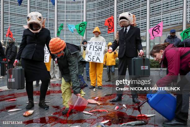 Activists pour red liquid used as blood on false fish during a demonstration by Ocean Rebellion a movement affiliate with Extinction Rebellion, in...