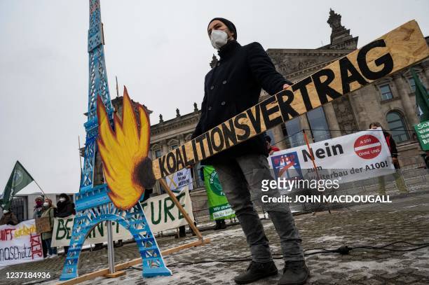 An activist holds a symbolic burning matchstick inscribed with the words "coalition contract", referring to the contract agreed upon by the current...