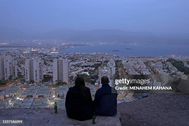 Couple sits on a hill in Israel's southern Red Sea coastal city of Eilat, where the 70th Miss Universe beauty pageant will take place, on December...