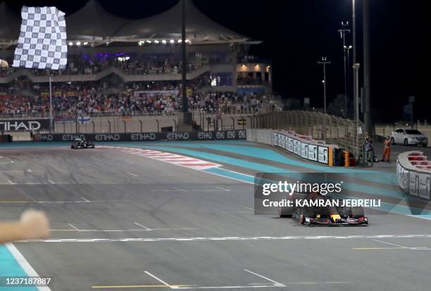 Formula One World Champion 2021 Red Bull's Dutch driver Max Verstappen crosses the finish line at the Yas Marina Circuit during the Abu Dhabi Formula...