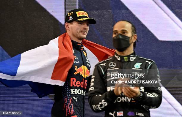 Formula One World Champion Red Bull's Dutch driver Max Verstappen walks past second-placed Mercedes' British driver Lewis Hamilton on the podium of...