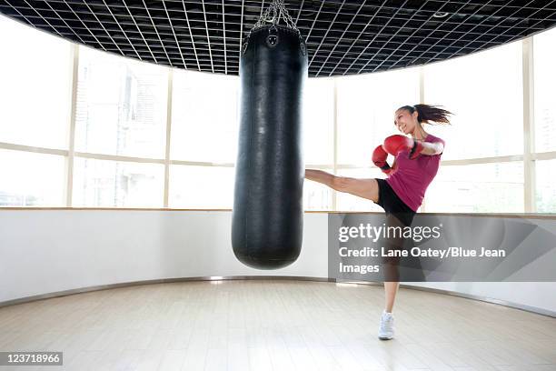 young woman kicking punching bag - boxboll bildbanksfoton och bilder