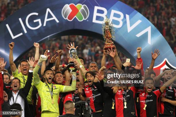 Atlas players celebrate with the trophy and a Virgin of Guadalupe after winning the Mexican Apertura tournament football final match against Leon at...