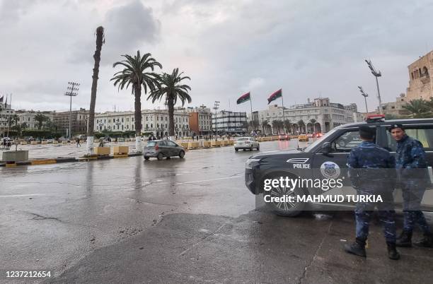 Policemen stand by a stationary patrol vehicle at the Martyrs' Square of Libya's capital Tripoli on December 13, 2021.