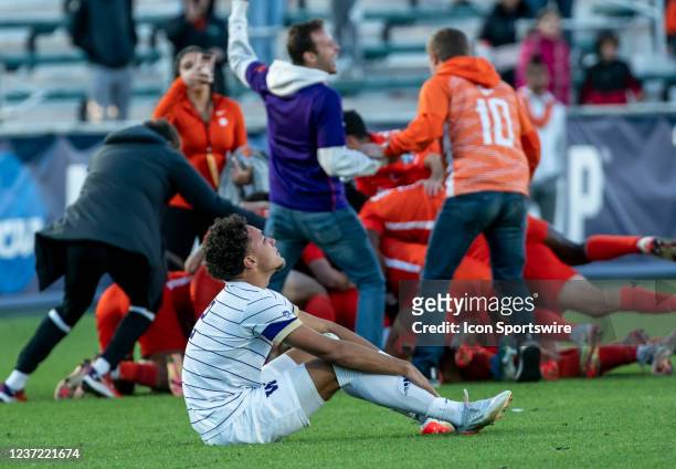 Victorious Clemson players celebrate behind Washington Huskies defender Kendall Burks during the NCAA Div 1 Mens College Cup final between the...