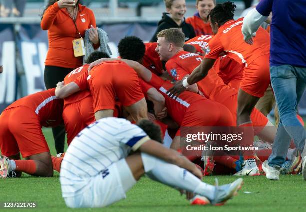 Victorious Clemson players celebrate behind Washington Huskies defender Kendall Burks during the NCAA Div 1 Mens College Cup final between the...