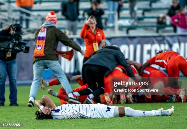 Victorious Clemson players celebrate behind Washington Huskies defender Kendall Burks during the NCAA Div 1 Mens College Cup final between the...