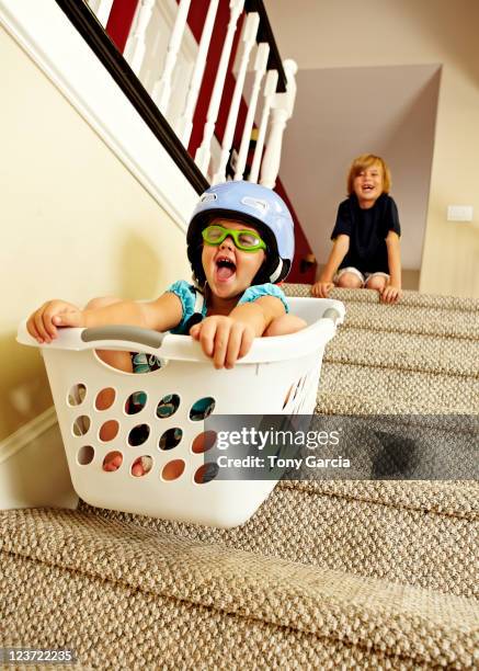 girl going downstairs in a laundry basket. - rutsche stock-fotos und bilder