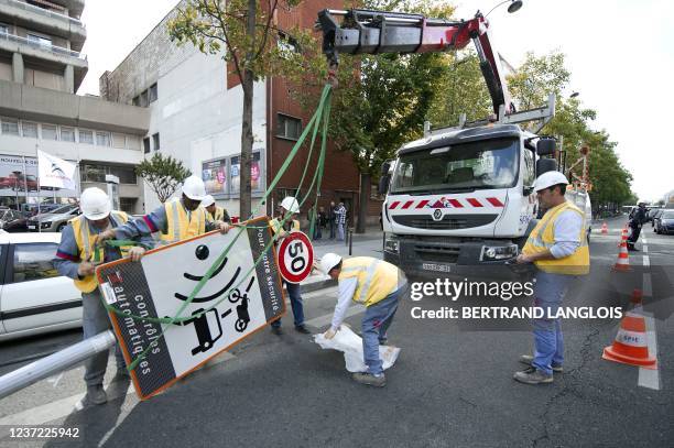 Des ouvriers de la société de services Spie démontent un panneau avertissant de la présence d'un radar fixe, le 16 mai 2011 à Paris. Il s'agit du...