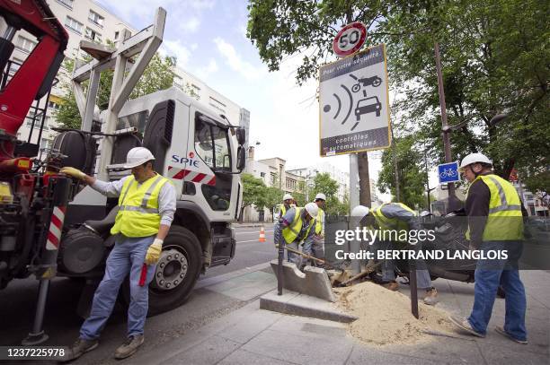 Des ouvriers de la société de services Spie démontent un panneau avertissant de la présence d'un radar fixe, le 16 mai 2011 à Paris. Il s'agit du...