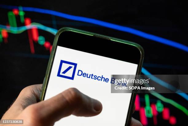 In this photo illustration the German investment bank and financial services, Deutsche Bank logo seen displayed on a smartphone with an economic...