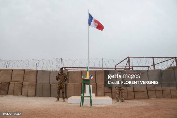 Malian and a French soldier stand on either side of the Barkhane camp flagpole before the handover ceremony of the Barkhane military base to the...