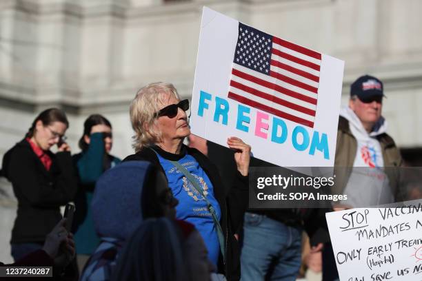 Protester is seen holding a placard that displays a flag of United States with a word that says "Freedom" during the protest against vaccination...