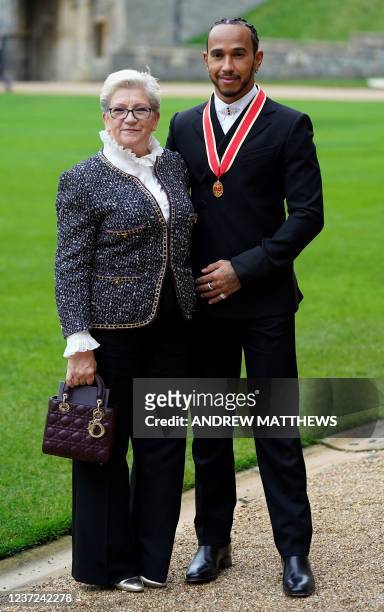 Mercedes' British driver Lewis Hamilton stands with his with his mother Carmen Lockhart, as he poses with his medal after being appointed as a Knight...