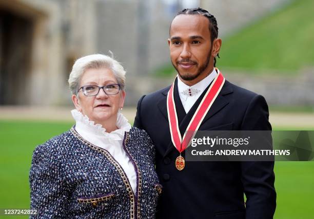 Mercedes' British driver Lewis Hamilton stands with his with his mother Carmen Lockhart, as he poses with his medal after being appointed as a Knight...
