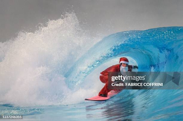 Surfer dressed as Santa Claus rides an artificial wave in a 0.6 degree cold water in the Alaia Bay surf wave pool surrrounded by Swiss Alps, in Sion,...