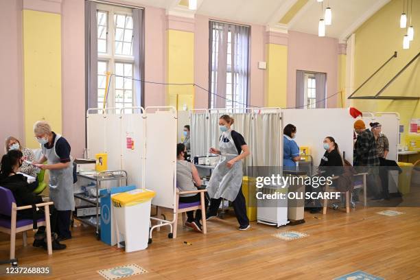 People wait to receive a dose of the Moderna Covid-19 vaccine at Babington Hospital in Belper on December 16, 2021 as the UK steps up the country's...