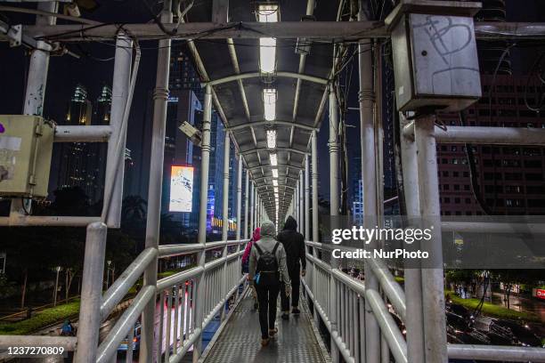 People wear protective face masks while walking at pedestrian bridge in business district on the main street in Jakarta on 16 December 2021. Health...