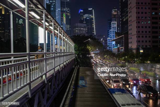 Man wear protective face masks while walking at pedestrian bridge in business district on the main street in Jakarta on 16 December 2021. Health...