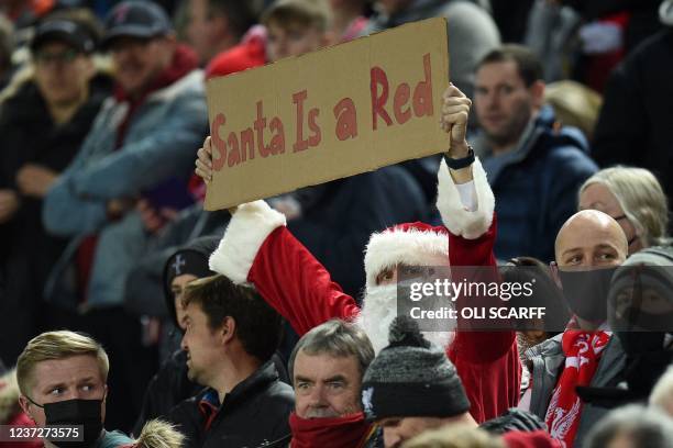 Fan wearing a Santa costume holds up a placard in the crowd ahead of the English Premier League football match between Liverpool and Newcastle United...