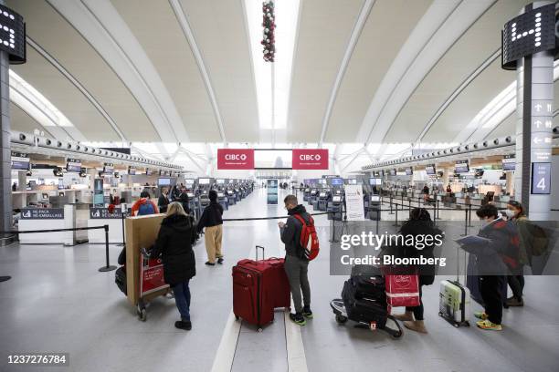 Travelers wait to enter the check-in area with their luggage at Toronto Pearson International Airport in Toronto, Ontario, Canada, on Thursday, Dec....