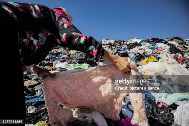 November 2021, Chile, Alto Hospicio: A woman searches for an item of clothing among a mountain of used clothes at a garbage dump. In the nearby free...
