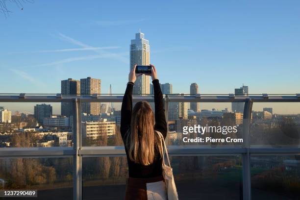Woman takes a photo of the skyline from the rooftop of Depot Boijmans Van Beuningen on December 16, 2021 in Rotterdam, Netherlands. Netherlands is...