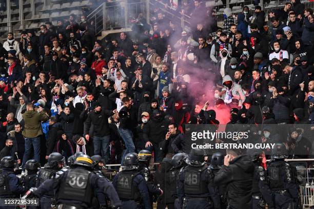 French anti-riot police officers arrive as supporters light a flare at half-time during the French Cup round of 64 football match between Paris FC...