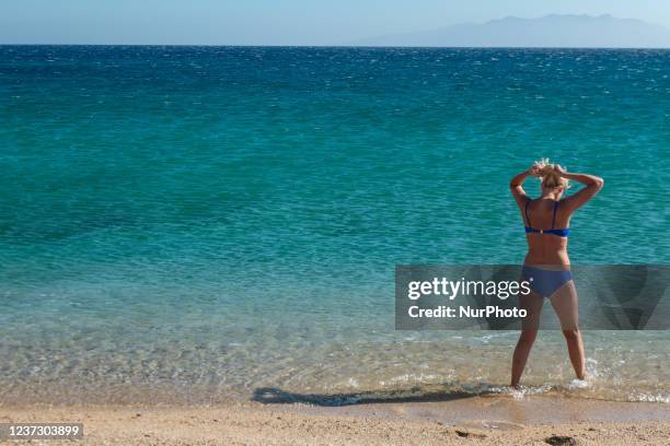 Woman with a bikini in the sea. Tourists as seen enjoying the sun, swimming, sunbathing and tanning at Paralia Lia beach in Mykonos island. A tourist...