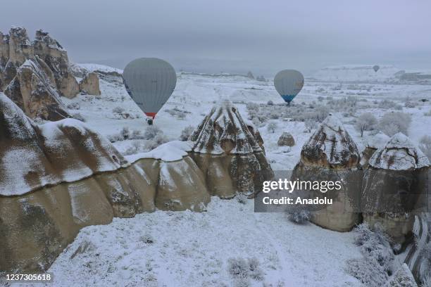 Drone photo shows hot-air balloons gliding above fairy chimneys in snow-covered Cappadocia region, located in Nevsehir province, Turkey on December...