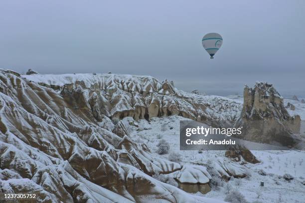 Hot-air balloons glide above fairy chimneys in snow-covered Cappadocia region, located in Nevsehir province, Turkey on December 18, 2021.