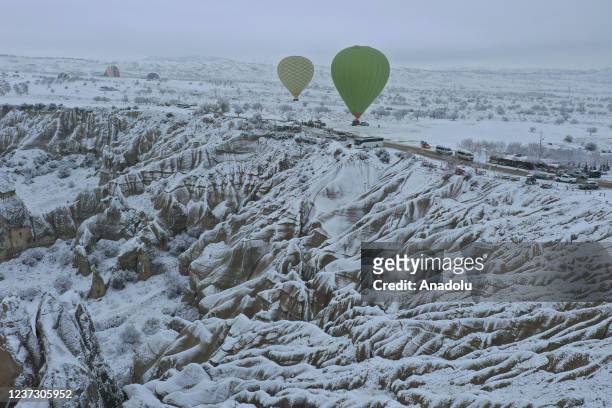 Hot-air balloons glide above fairy chimneys in snow-covered Cappadocia region, located in Nevsehir province, Turkey on December 18, 2021.