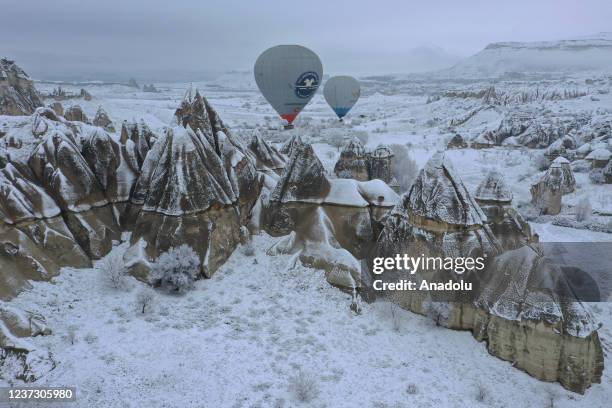 Drone photo shows hot-air balloons gliding above fairy chimneys in snow-covered Cappadocia region, located in Nevsehir province, Turkey on December...