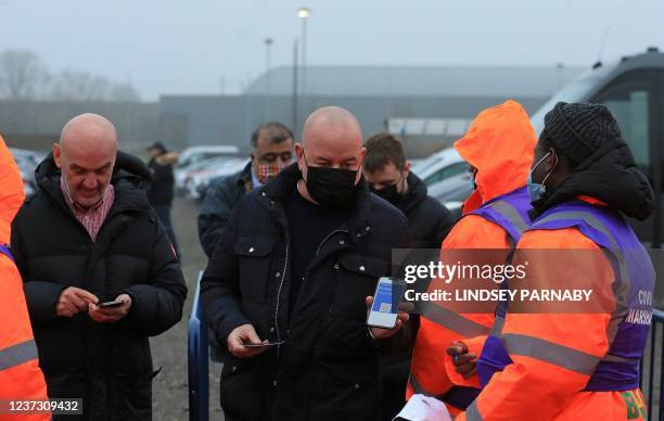 Covid-19 Marshalls check the status of a fan's NHS Covid Pass as they arrive to attend the English Premier League football match between Leeds United...